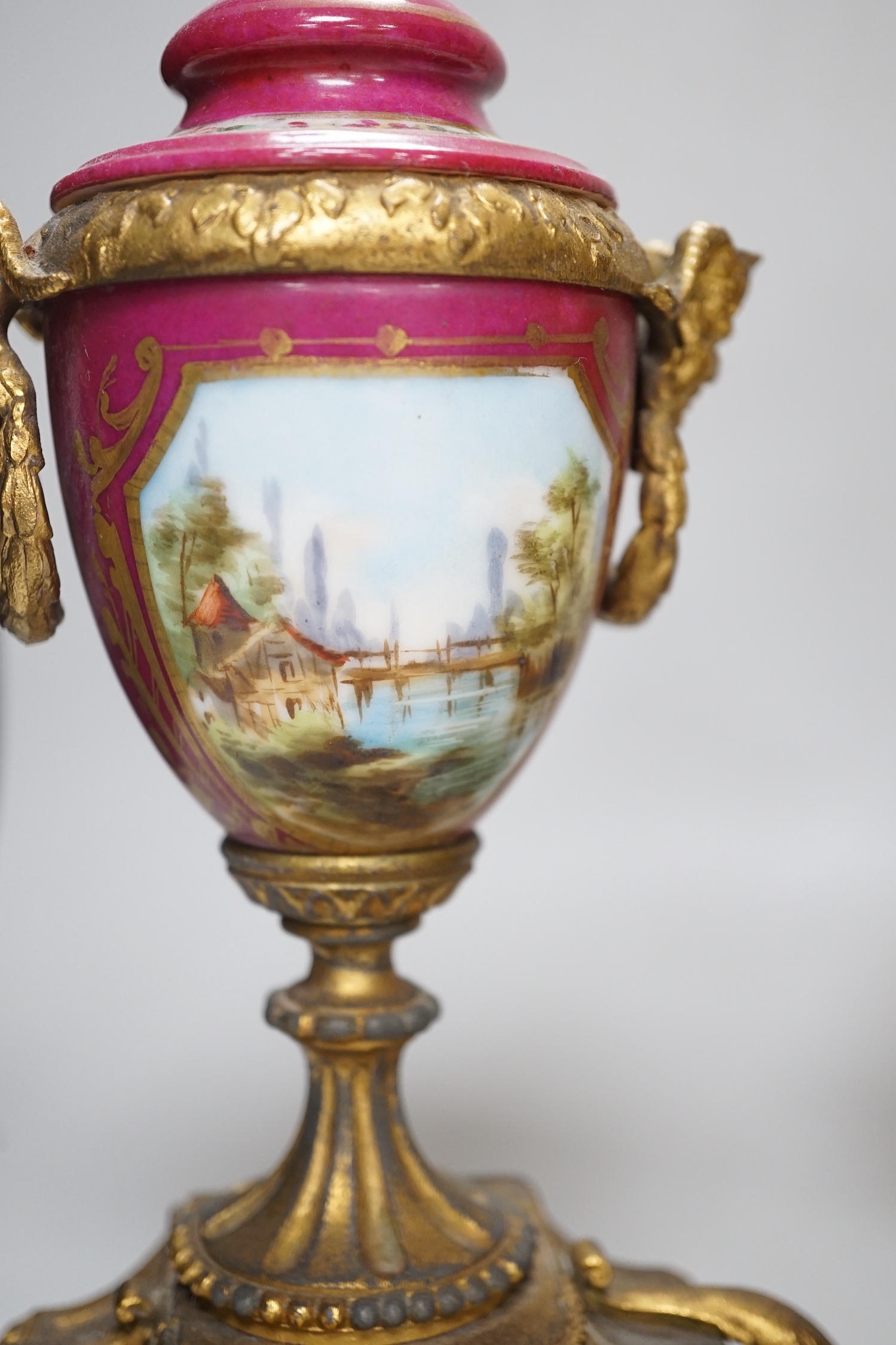 A 19th century porcelain mounted gilt spelter clock garniture, hand painted with landscapes, 30cm high